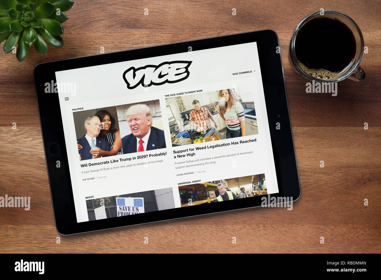 Die Website von Vice ist auf einem iPad Tablet gesehen, auf einer hölzernen Tisch zusammen mit einem Espresso und einem Haus Anlage (nur redaktionelle Nutzung). Stockfoto