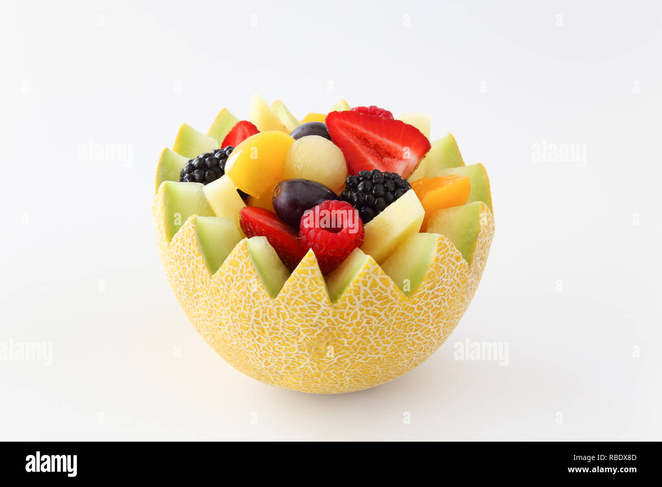 Fancy cut Melone auf einem weißen Hintergrund mit sortierten Obst wie Erdbeeren, Himbeeren, Weintrauben, Pfirsiche, Ananas, in Scheiben geschnitten und Brombeeren Stockfoto