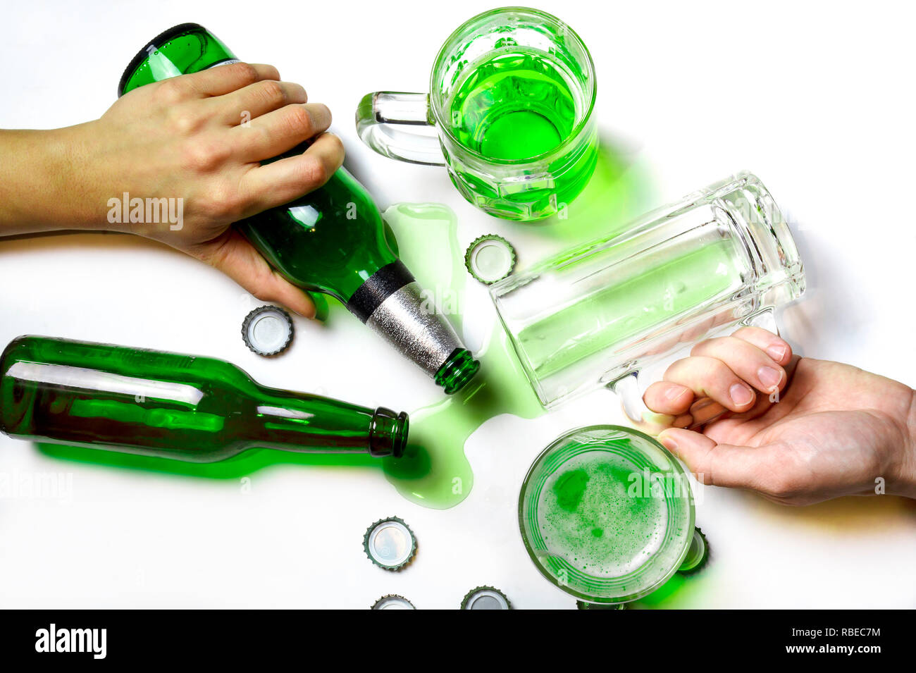 St. Patrick's Day after Party Konzept. Gläser und Flaschen grün Bier auf unordentliche weißer Tisch mit Bier Kappen Stockfoto