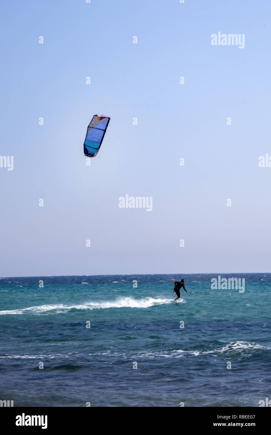 Auf ein Wakeboard Fliegen ein Traction Kite Surfer. Reiter im Neoprenanzug  stehen und Balancieren auf einem Surfbrett. Blaues Wasser und klaren  Himmel. Wassersport Abenteuer ICH Stockfotografie - Alamy