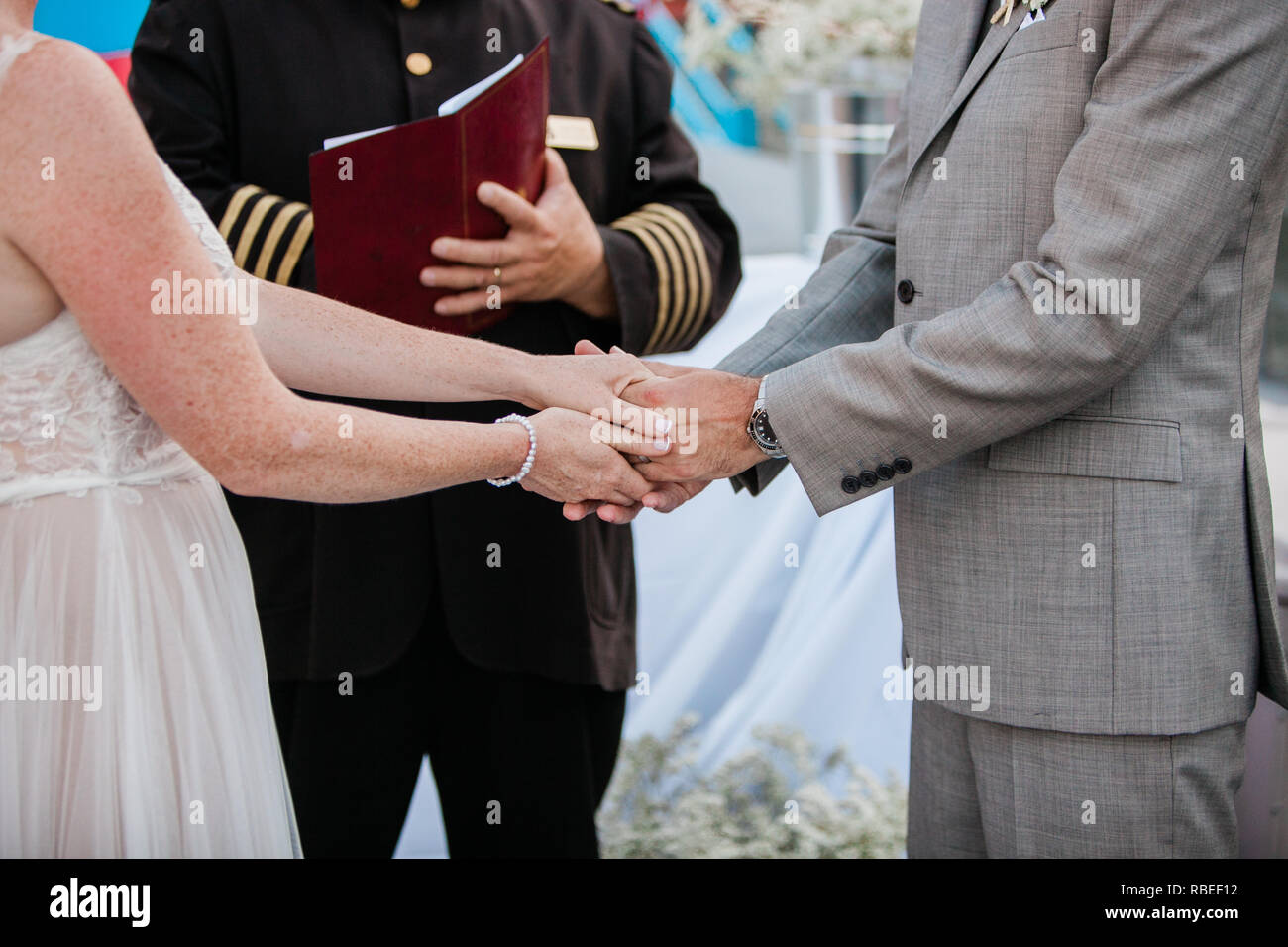 Braut und Bräutigam, Hände halten während der Zeremonie mit Dienstleiter Stockfoto