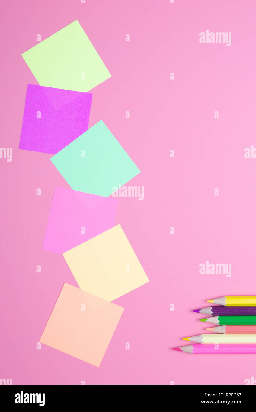 Buntstifte und farbiges Papier auf rotem Hintergrund Stockfoto