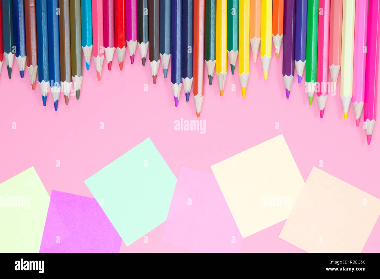 Buntstifte und farbiges Papier auf rotem Hintergrund Stockfoto