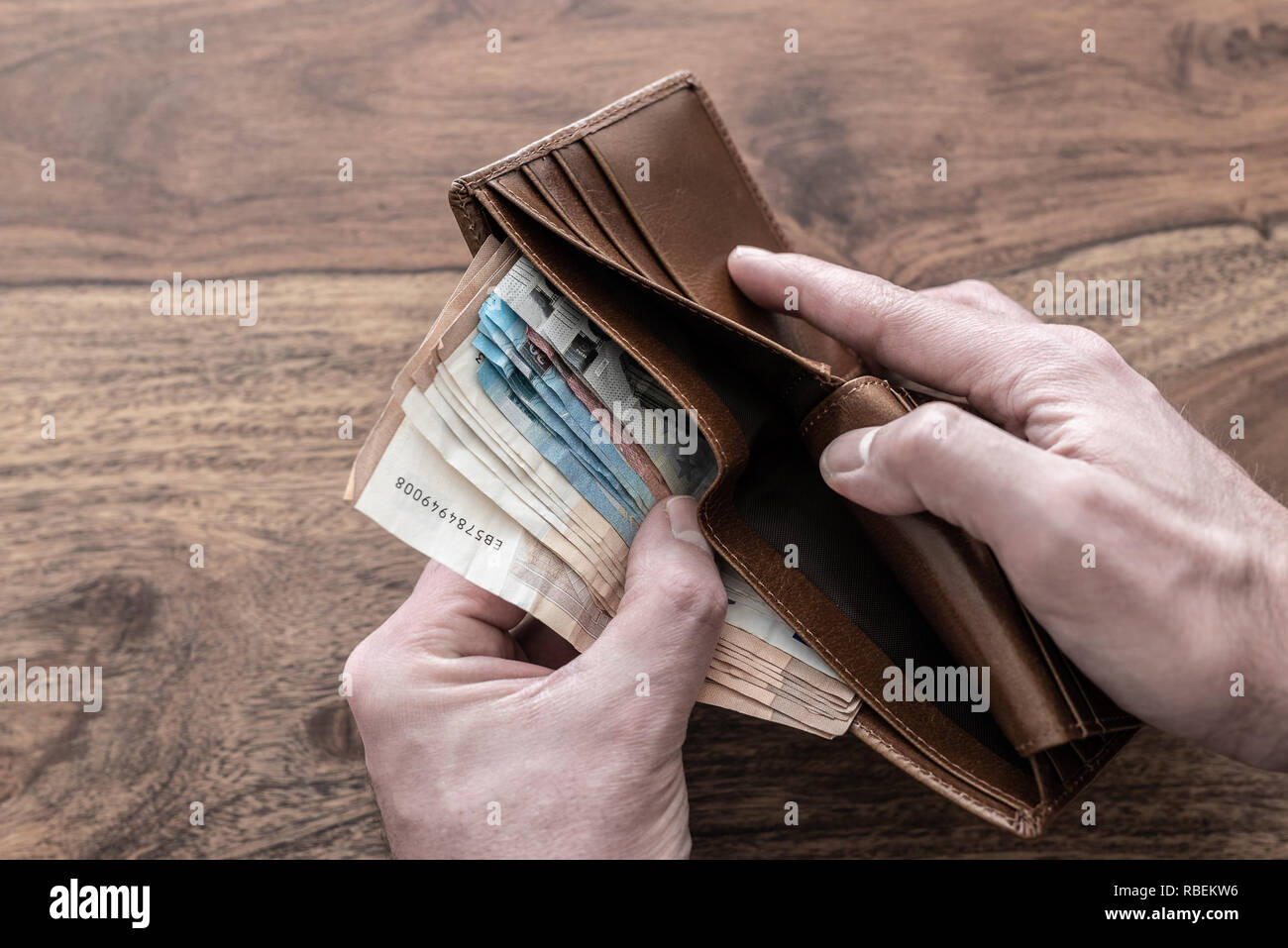 Hände, die Stapel von Bargeld aus der Brieftasche Stockfoto