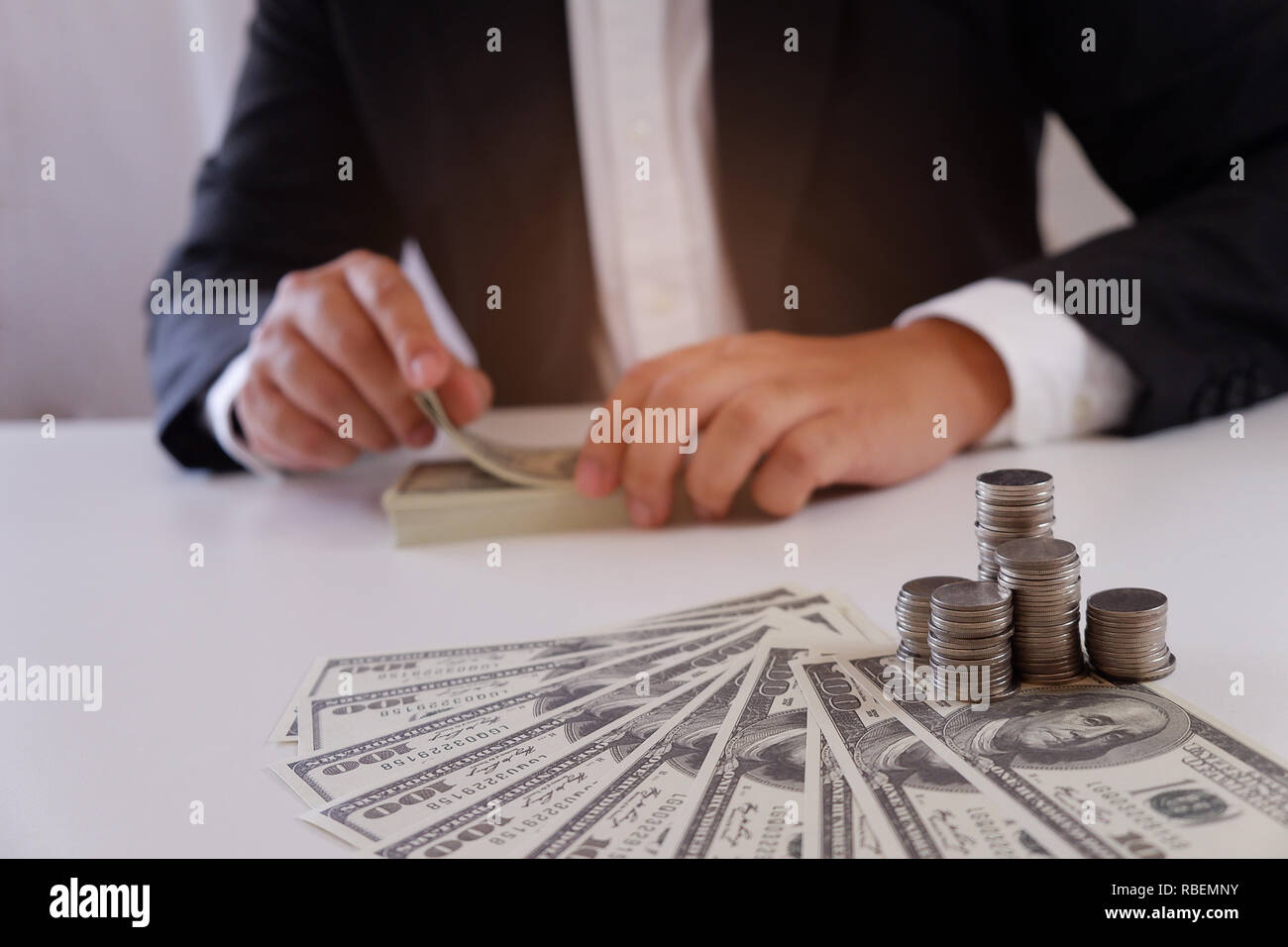 Unternehmer zählen Geld mit Münzen und Geld über den Schreibtisch Stockfoto