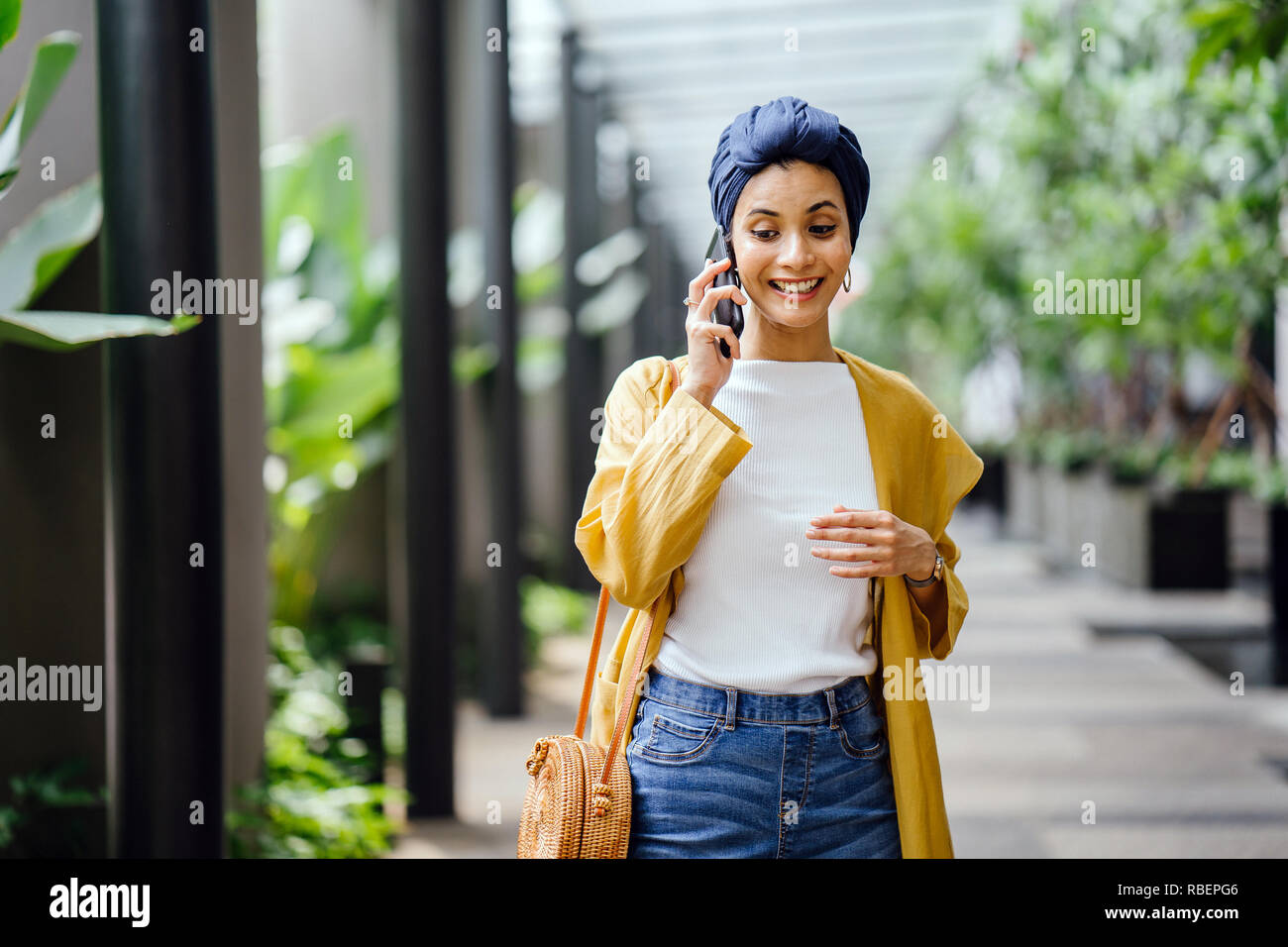 Eine junge und schöne Orientalische Frau in einem turban Hijab ist Lächeln, wie Sie auf Ihrem Smartphone die Gespräche auf der Straße während des Tages. Stockfoto