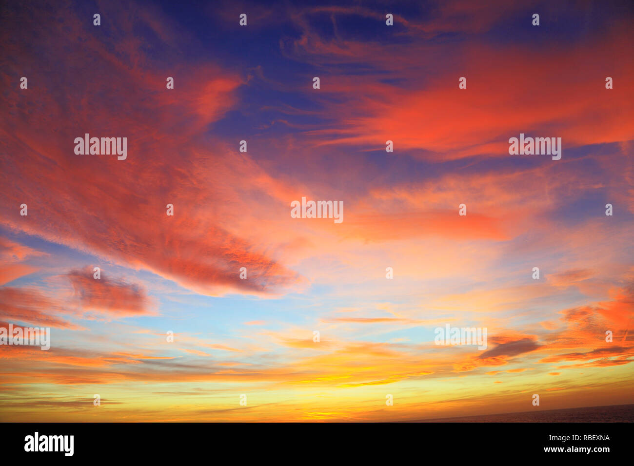 Die untergehende Sonne, Sonnenuntergang, rot, rosa, orange, gelb, Wolken, blauer Himmel, Himmel, dramatisch, Farbe, bunte Stockfoto
