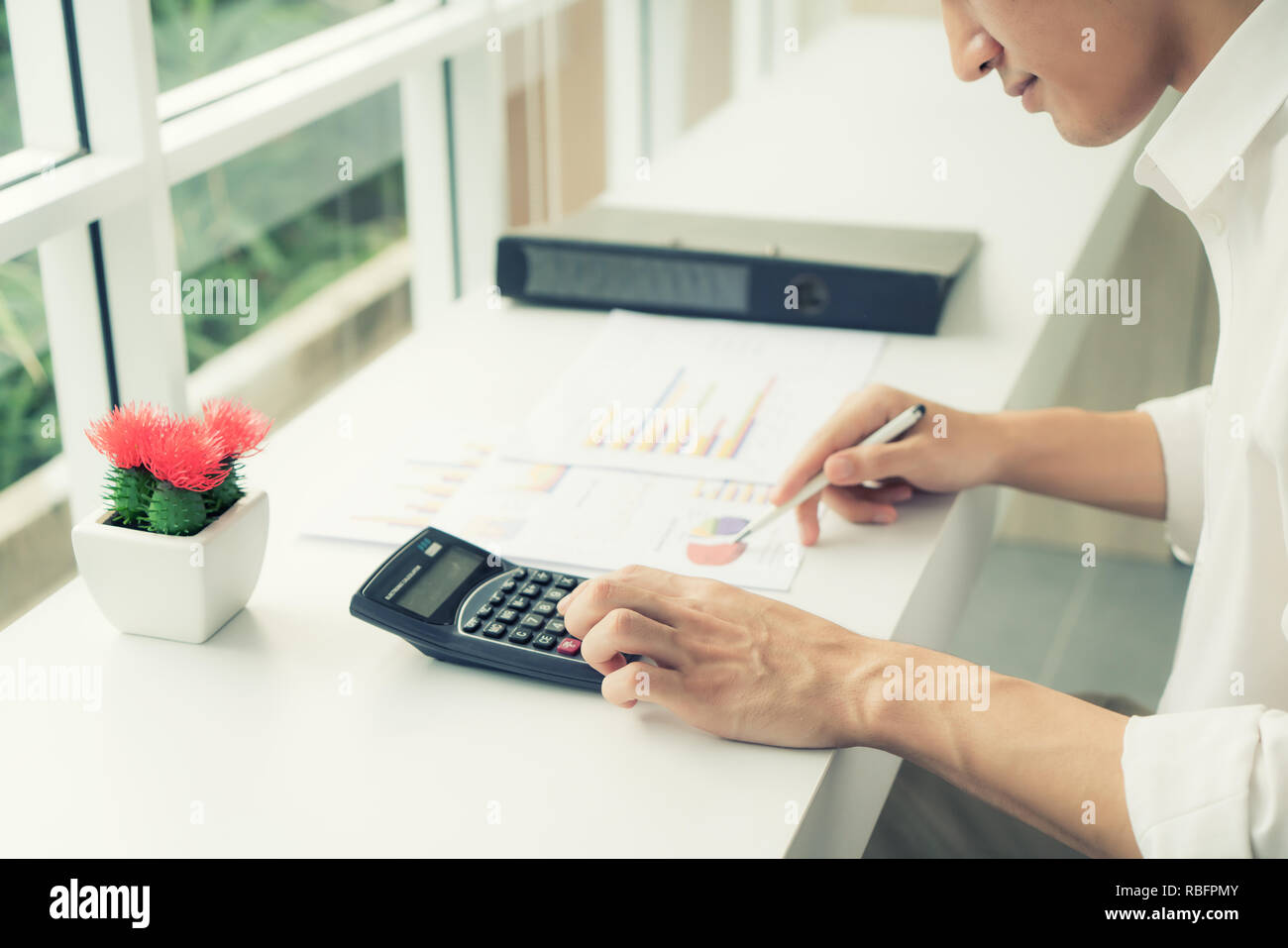 Asiatische Geschäftsmann mit einem Taschenrechner die Zahlen auf seinem Schreibtisch zu berechnen. Buchhalter Berechnung der Finanzen. Stockfoto