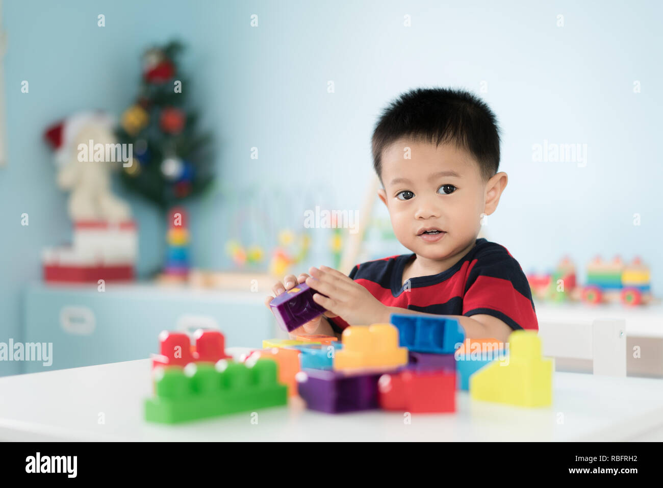 Adorable asiatischen Kleinkind Baby Junge sitzt auf einem Stuhl und Spielen mit Farbe block Spielzeug zu Hause. Stockfoto