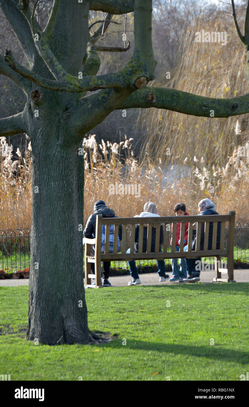 St James's Park im Winter, London, England, UK. Familie sitzt auf einer Bank Stockfoto