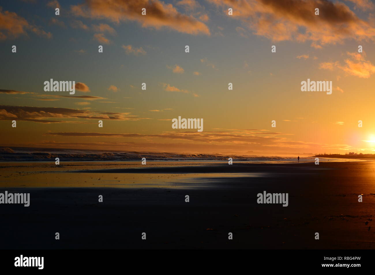 Dramatischer sonnenaufgang Farben; schönen Sonnenaufgang am Strand und eine einsame Figur einer Person zu Fuß am Strand entlang. Stockfoto