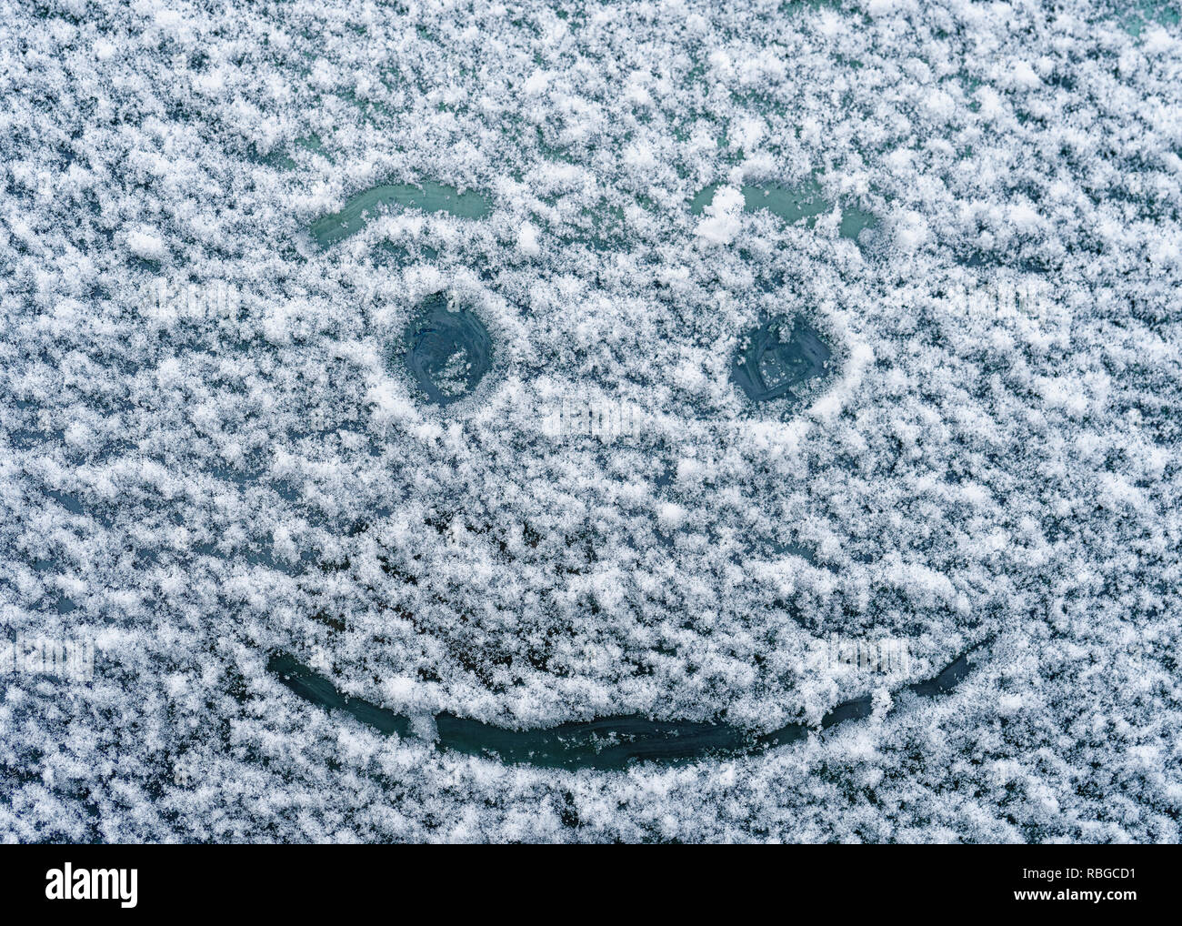 Ein glückliches Gesicht gezeichnet auf einem schneebedeckten Windschutzscheibe. Stockfoto