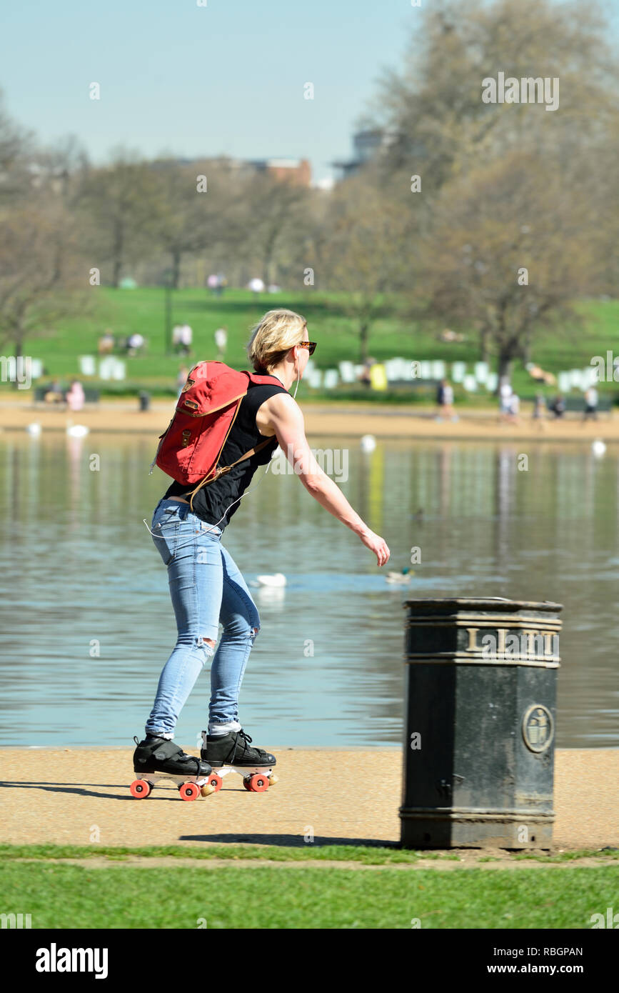 Junge Frau Roller Skating Neben der Serpentine, Hyde Park, London, Vereinigtes Königreich Stockfoto