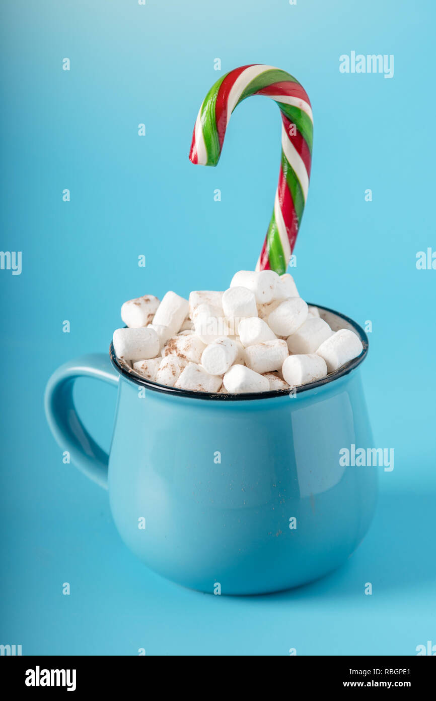 Tasse heiße Schokolade mit Marshmallows auf und halten einen Lutscher auf einem blauen Hintergrund. Gemütliche warme Winter Karte Stockfoto