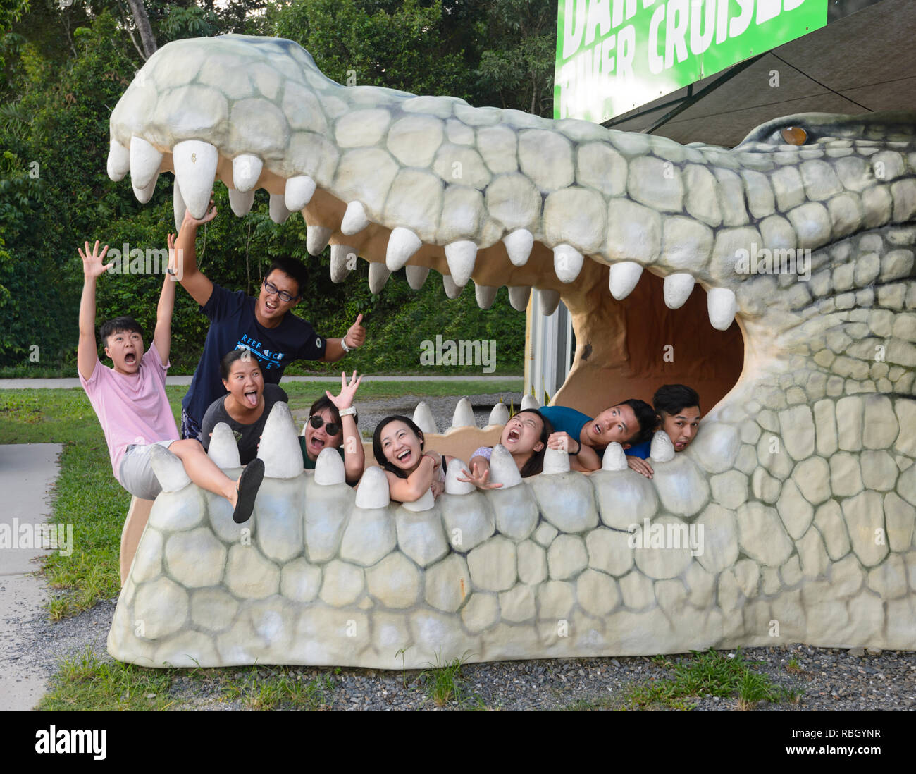 Eine Gruppe von chinesischen Touristen in den offenen Mund eines Krokodils Statue im Daintree River posing Kreuzfahrten Buchen Kiosk, Daintree Nationalpark, weit Nort Stockfoto