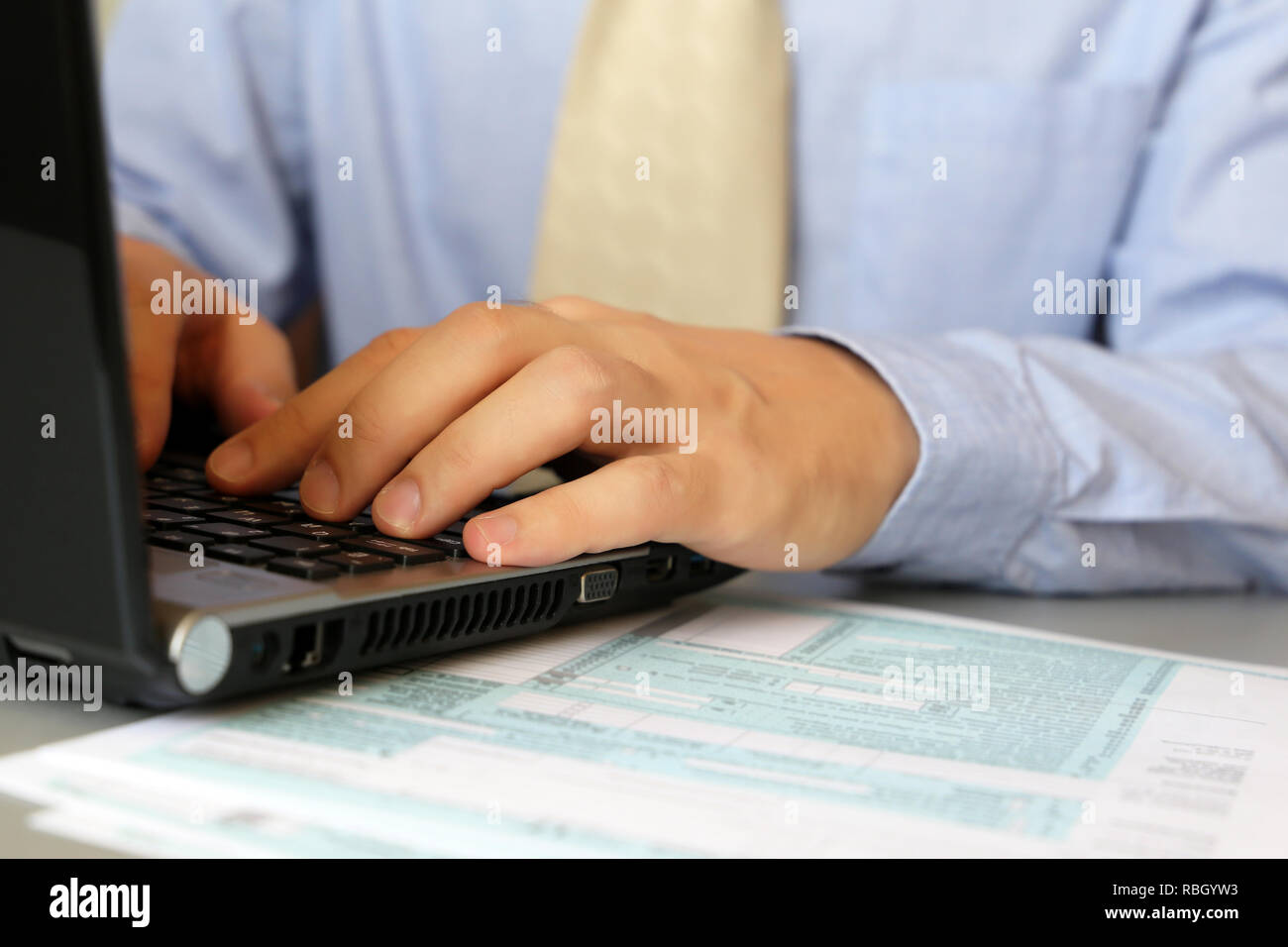 Mann im blauen Hemd und Krawatte arbeiten, an einem Tisch mit Laptop sitzen. Männliche Hände schreiben auf Tastatur, Konzept der Office Manager, Personal, Abschluss der Ta Stockfoto