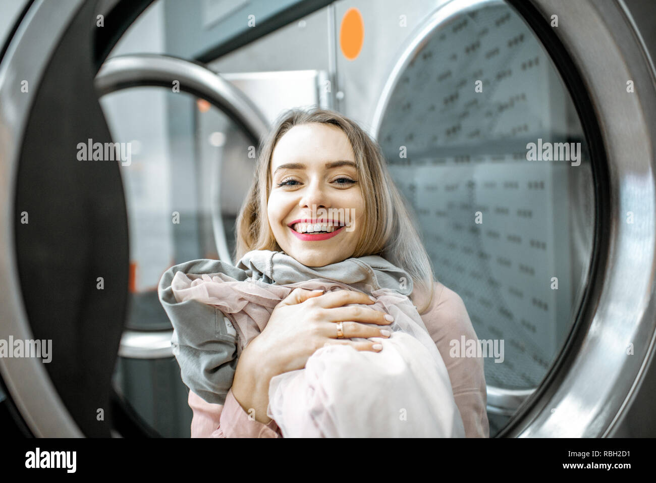 Porträt eines fröhliche Frau mit sauberem und getrocknete Kleidung in der Wäscherei Stockfoto