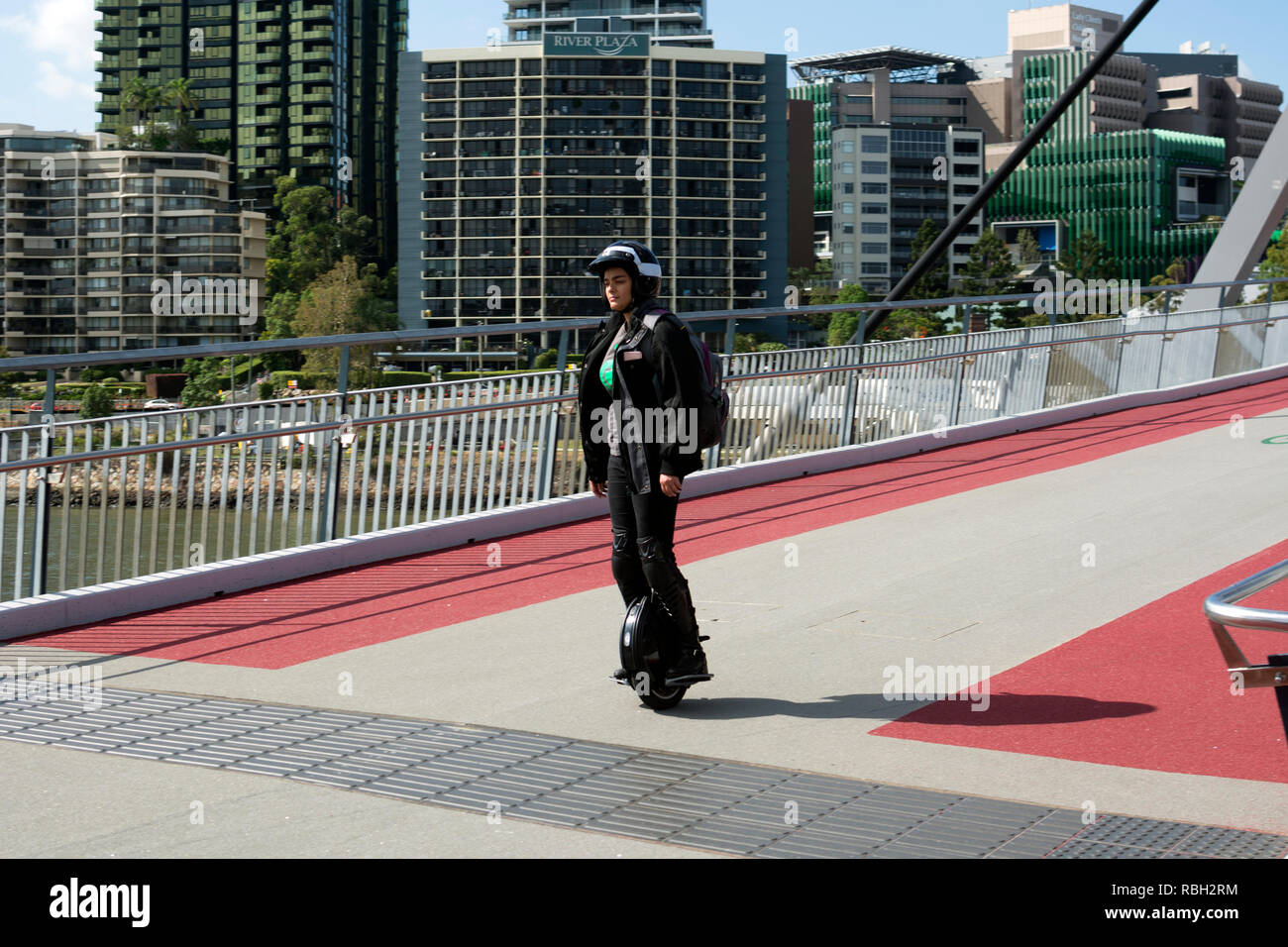 Eine Frau, eine elektrische Einrad über Goodwill Bridge, Brisbane, Queensland, Australien Stockfoto