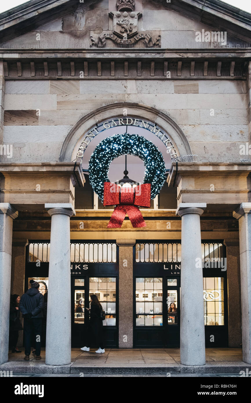 London, Großbritannien - 5. Januar 2019: Menschen zu Fuß unter Weihnachten Kranz Dekorationen an der Fassade der Covent Garden Market, einer der beliebtesten touristischen Stockfoto