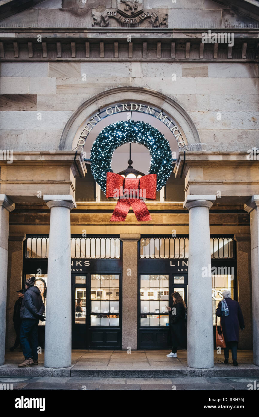 London, Großbritannien - 5. Januar 2019: Menschen zu Fuß unter Weihnachten Kranz Dekorationen an der Fassade der Covent Garden Market, einer der beliebtesten touristischen Stockfoto
