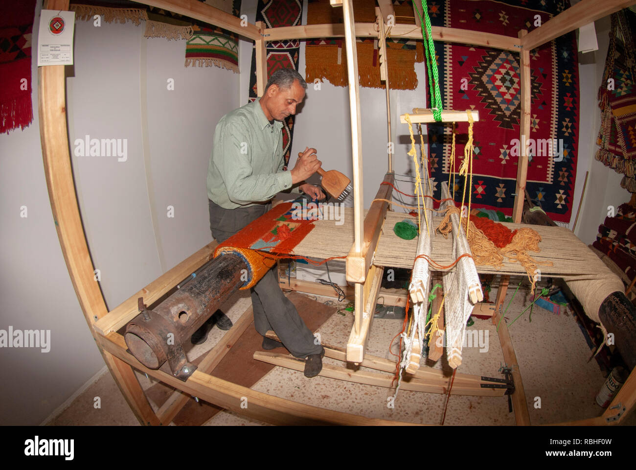 Hand webt einen wollenen Teppich auf dem Webstuhl zu einem Kunsthandwerksladen in Madaba Jordanien Stockfoto