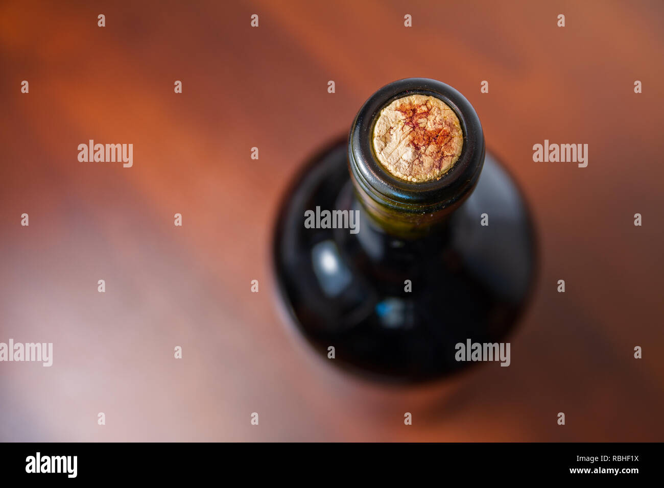 Dunkle Rotwein Flasche auf einem dunklen Holztisch mit dem Korken im Fokus Stockfoto