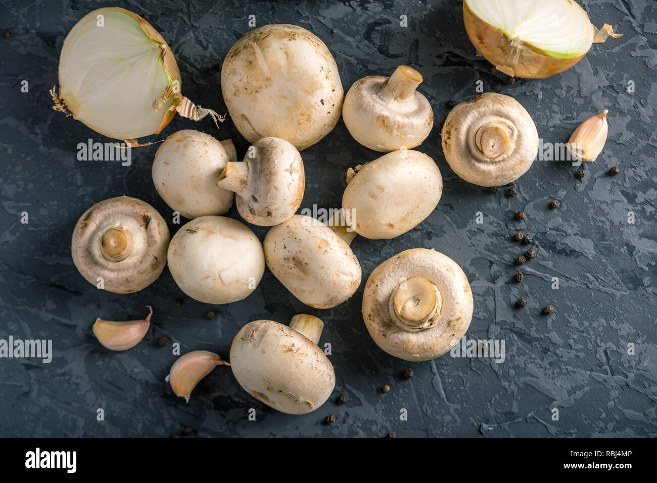 Frische weiße Champions, Gewürze und Zutaten auf der dunklen Küche Tisch. Das Konzept der Küche Pilzgerichte Stockfoto