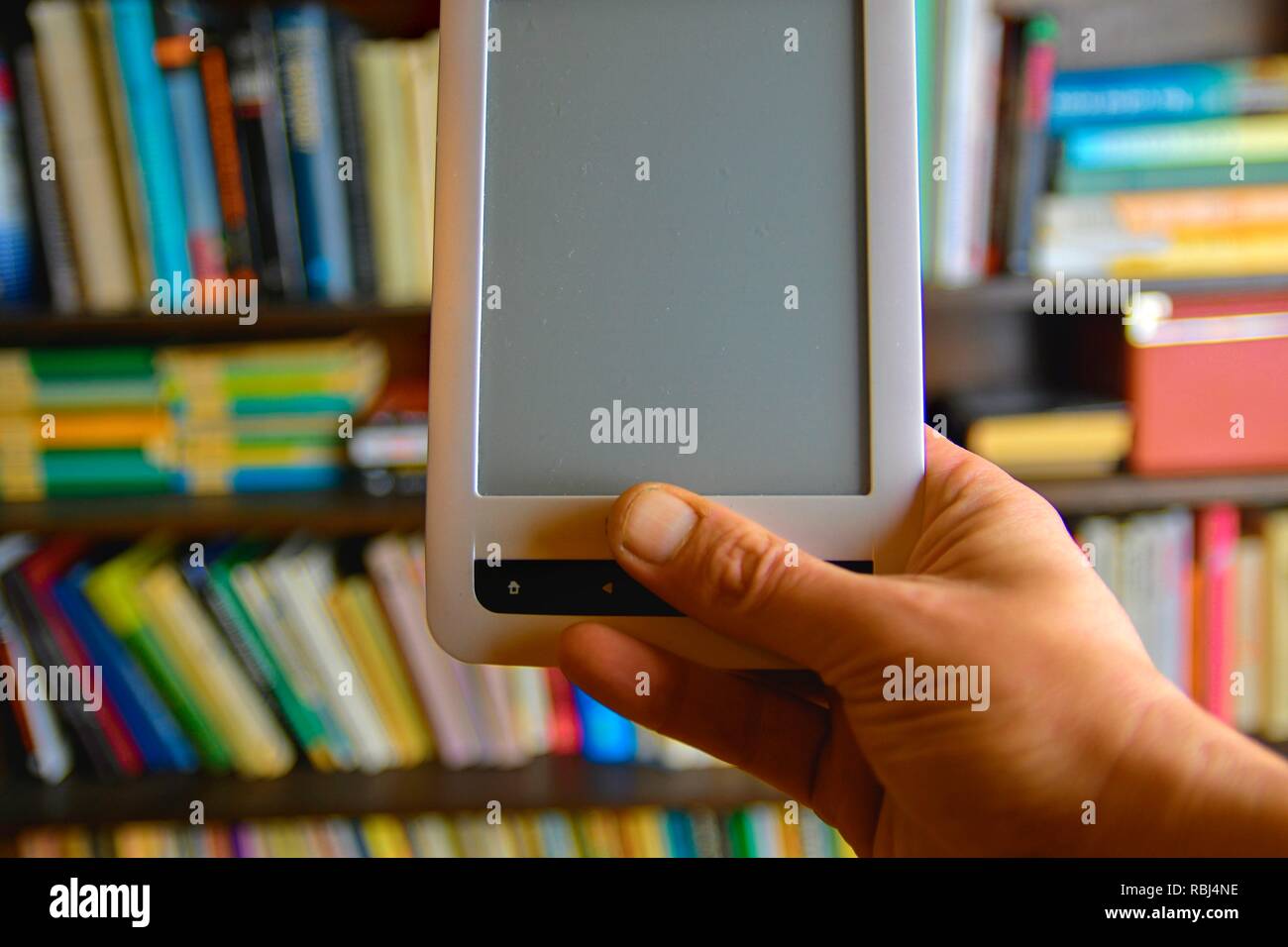 Hand e-Buch. Bibliothek die Regale im Hintergrund, e-Learning - Konzept. E-Buch in der Hand des Menschen Stockfoto