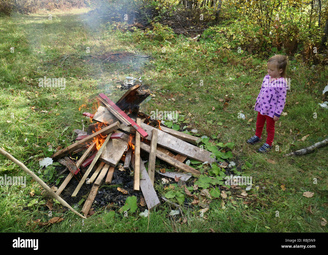 Ein kleines Mädchen (4 Jahre alt) an einem Lagerfeuer suchen Stockfoto