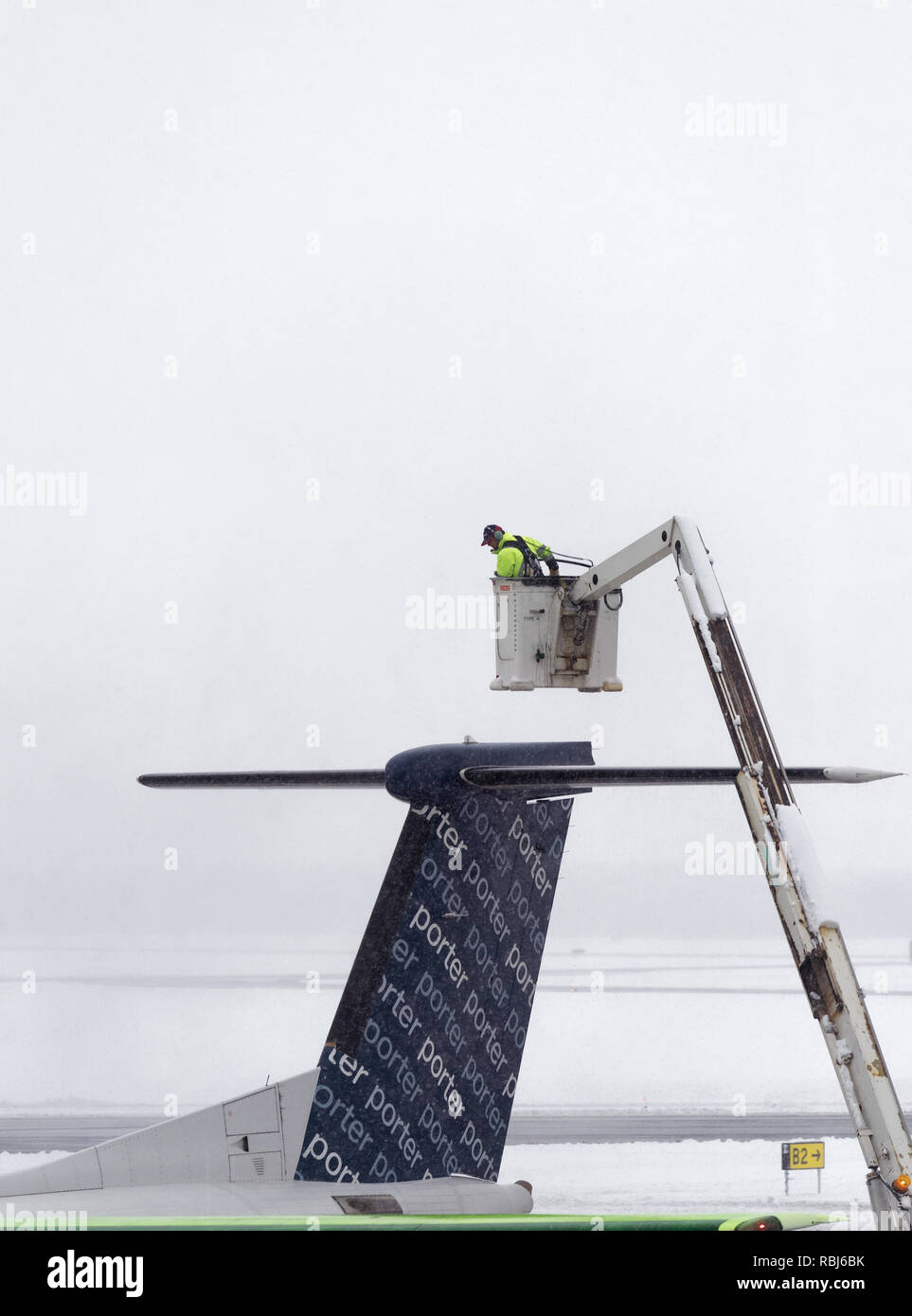 Ein Flughafen Mitarbeiter sprühen Heckscheibenheizung am Flügel eines Flugzeugs im Winter, das Flugzeug bereit für die Abreise. Die Stadt Quebec Jean Lesage Flughafen. Stockfoto