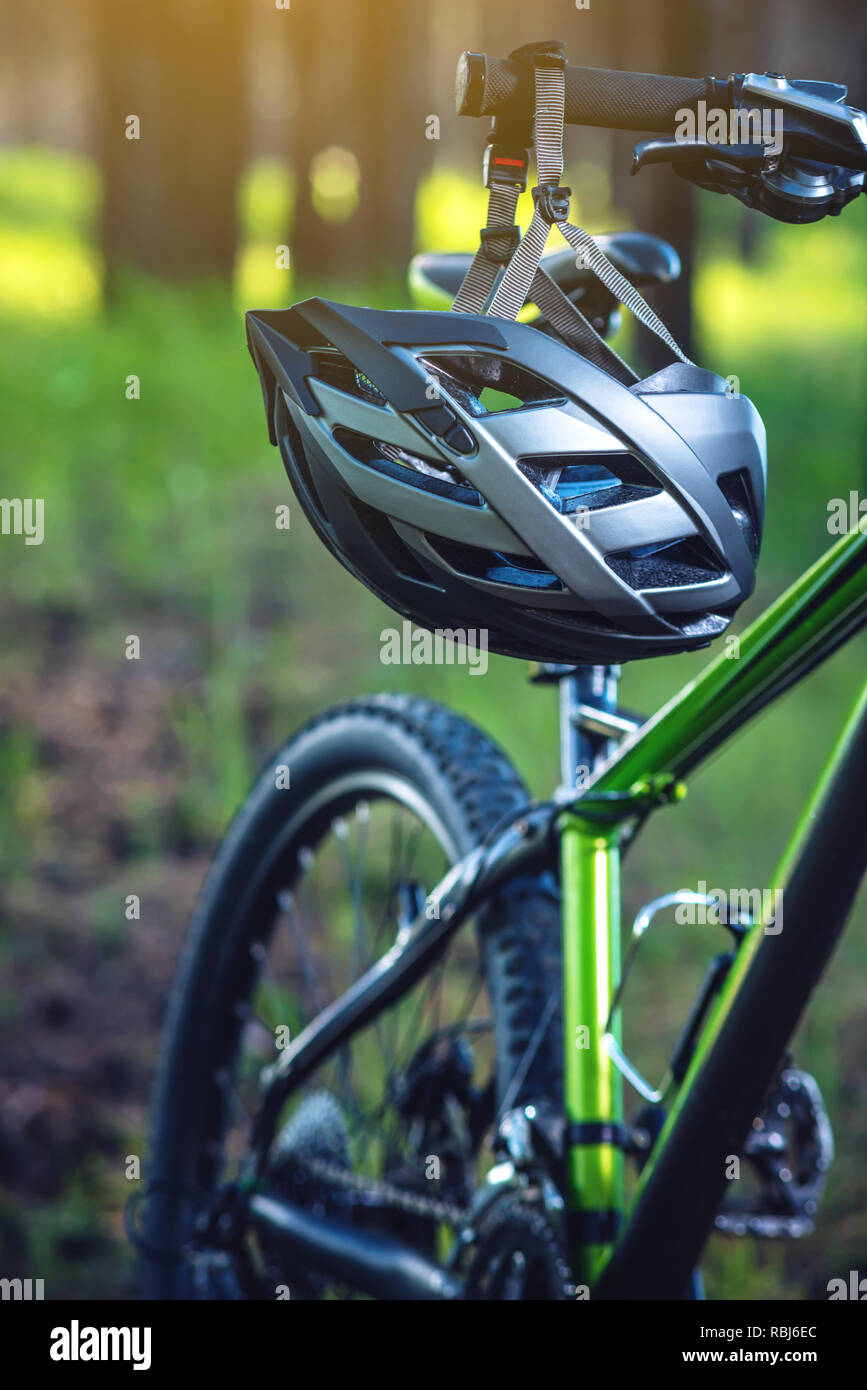 Sport Helm auf ein grünes Mountainbike im Park unter den Bäumen. Konzept Schutz während des aktiven und gesunden Lebensstil Stockfoto