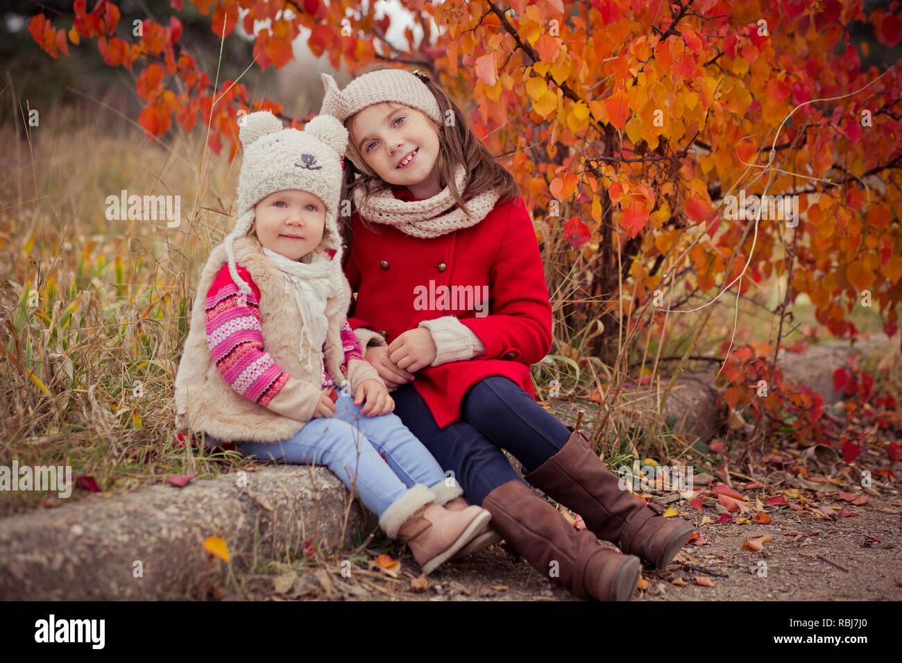 Mode Baby Mädchen Schwestern stilvoll gekleidet brunnette und blond tragen  warme Herbst Kleidung Jacken zusammen Posieren gerne in bunten Wald Laub. F  Stockfotografie - Alamy