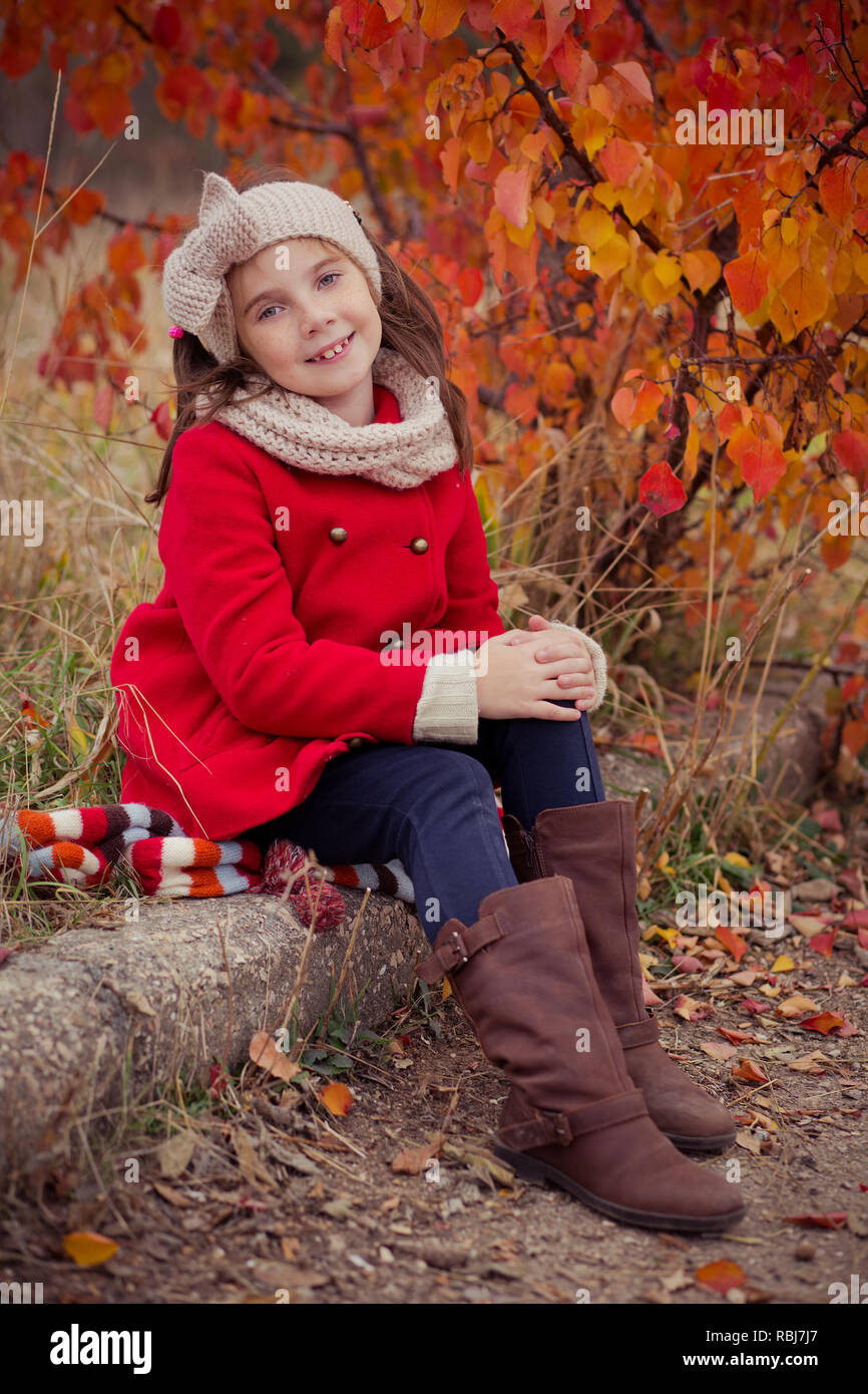 Nette junge russische Mädchen stilvoll in warmen Rot handgefertigte jacke jeans Stiefel und angespannt Stirnband Schal posiert im Herbst bunte Wald pathwa gekleidet Stockfoto