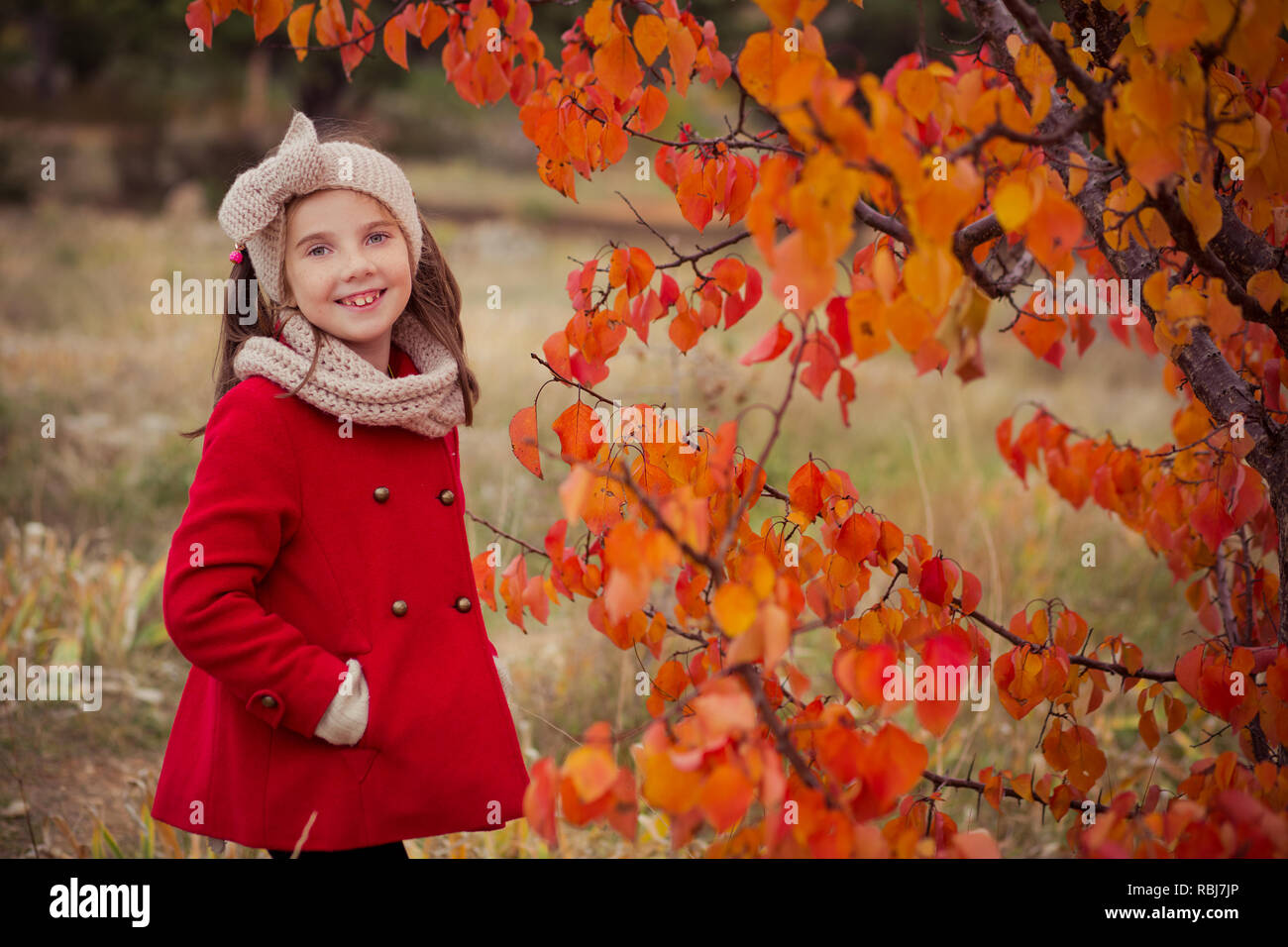 Nette junge russische Mädchen stilvoll in warmen Rot handgefertigte jacke jeans Stiefel und angespannt Stirnband Schal posiert im Herbst bunte Wald pathwa gekleidet Stockfoto