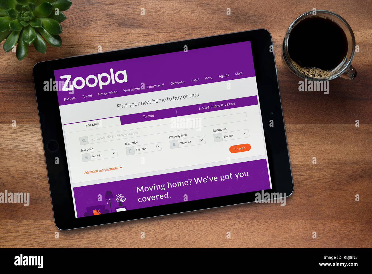 Die Website von zoopla ist auf einem iPad Tablet gesehen, auf einer hölzernen Tisch zusammen mit einem Espresso und einem Haus Anlage (nur redaktionelle Nutzung). Stockfoto