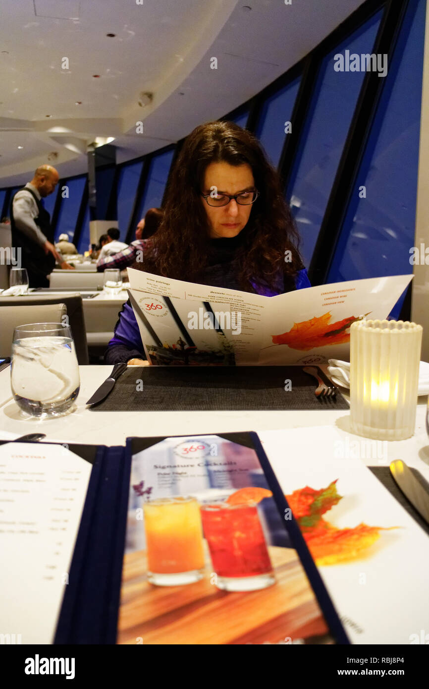 Eine Frau, die beim Lesen der Speisekarte im Restaurant 360˚ oben auf den CN Tower in Toronto Stockfoto