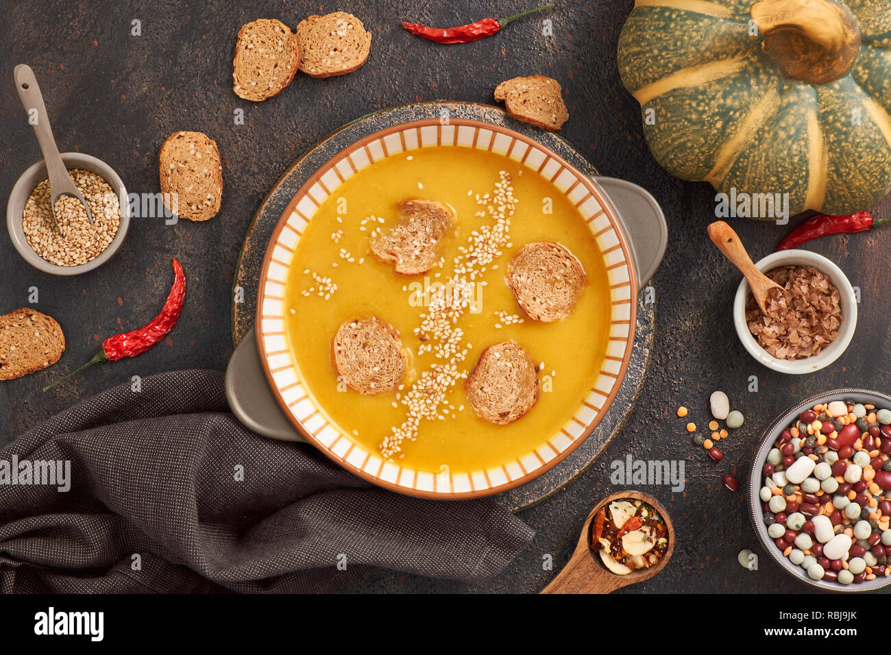 Kürbis und gemischte beanscreme Suppe in Keramik Schüssel, Ansicht von oben mit Zutaten und Gewürze, Ansicht von oben auf dunklem Hintergrund Stockfoto