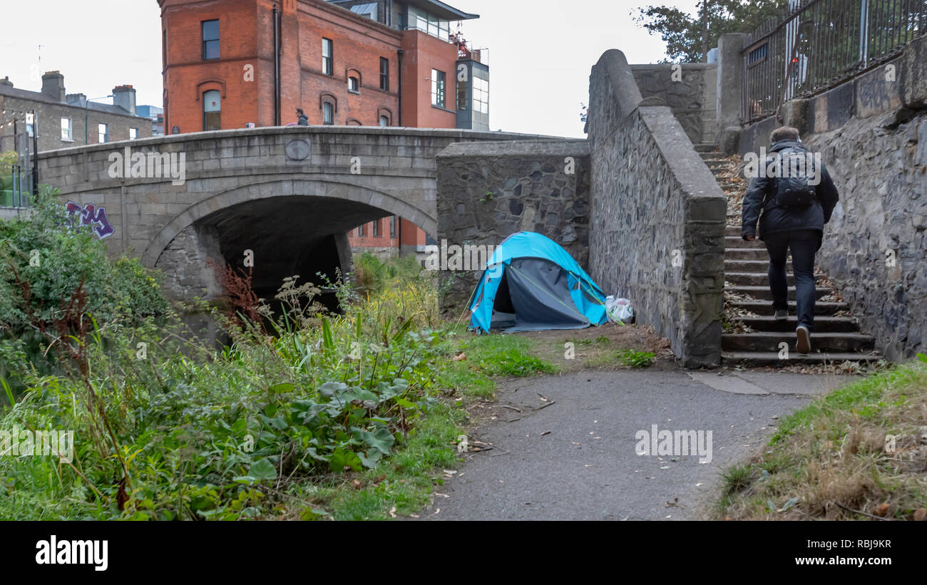 Ein Zelt für jemand obdachlos und ein Mann zu Fuß von der Grand Canal Waterway in Dublin, Irland. Stockfoto