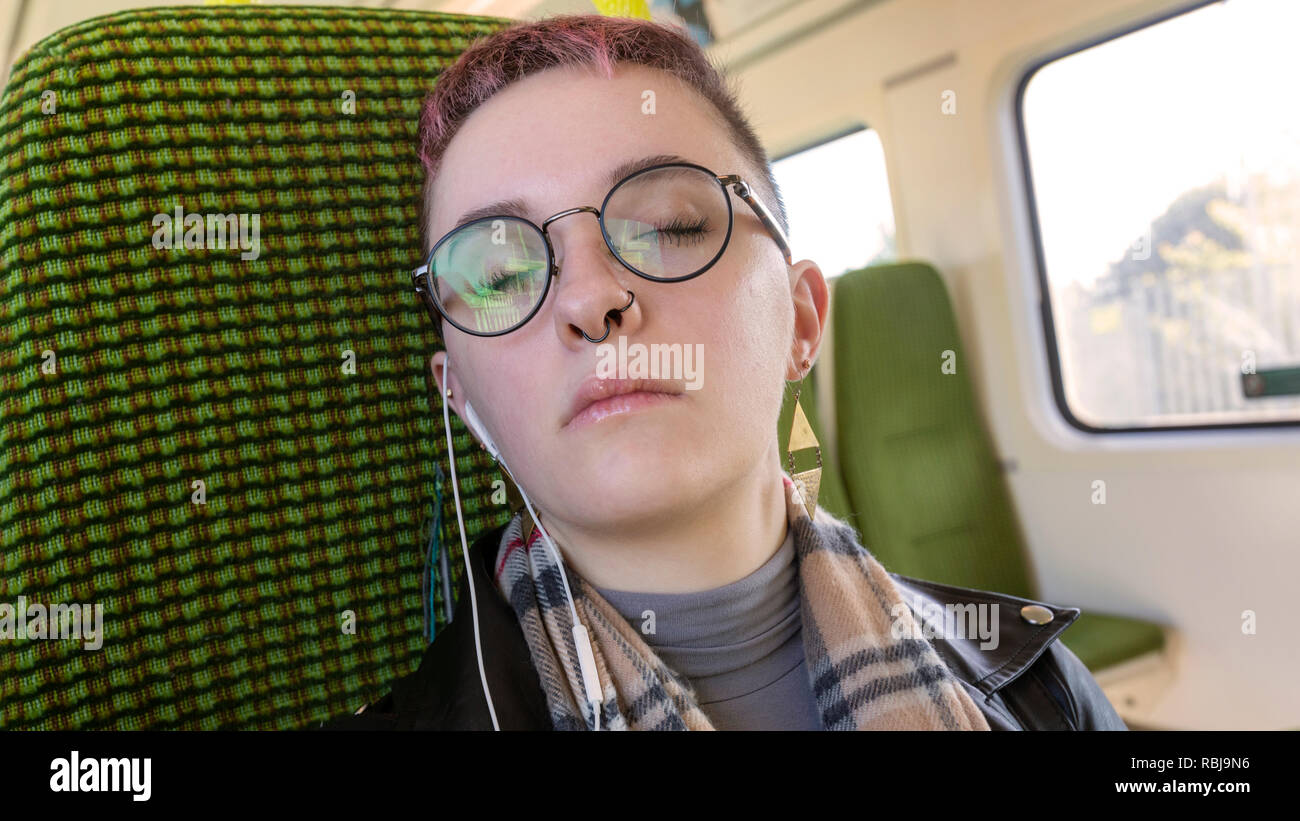Junge Frau, die ihre Augen ruhen und Reiten auf den DART, öffentliche Verkehrsmittel, in Dublin, Irland. Stockfoto