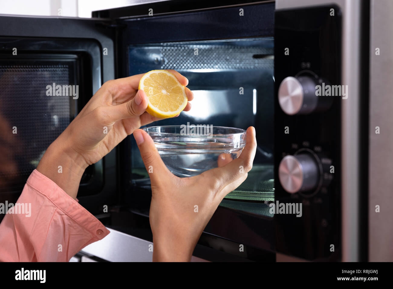 Woman's Hand zusammendrücken halbierte Zitrone in die Glasschale in der  Nähe von Offenen Mikrowelle Stockfotografie - Alamy