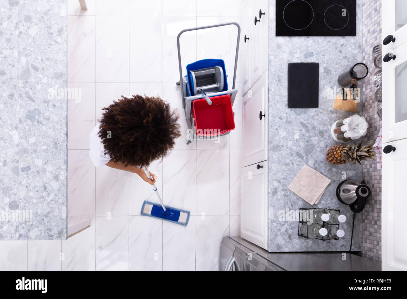 Weibliche Hausmeister Der weiße Stock mit Mop Reinigung in der modernen Küche Stockfoto