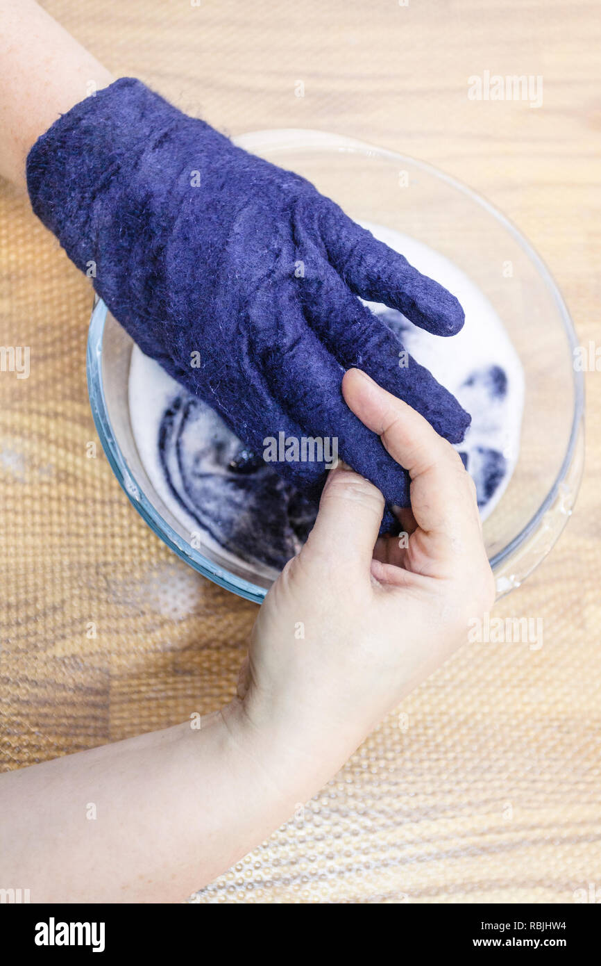 Werkstatt von Hand eine Fleece Handschuhe von blau Merino Schafschurwolle  nass Filzen Prozess - Handwerker passt die Größe der gefilzten Handschuh  mit heißem Wasser Stockfotografie - Alamy