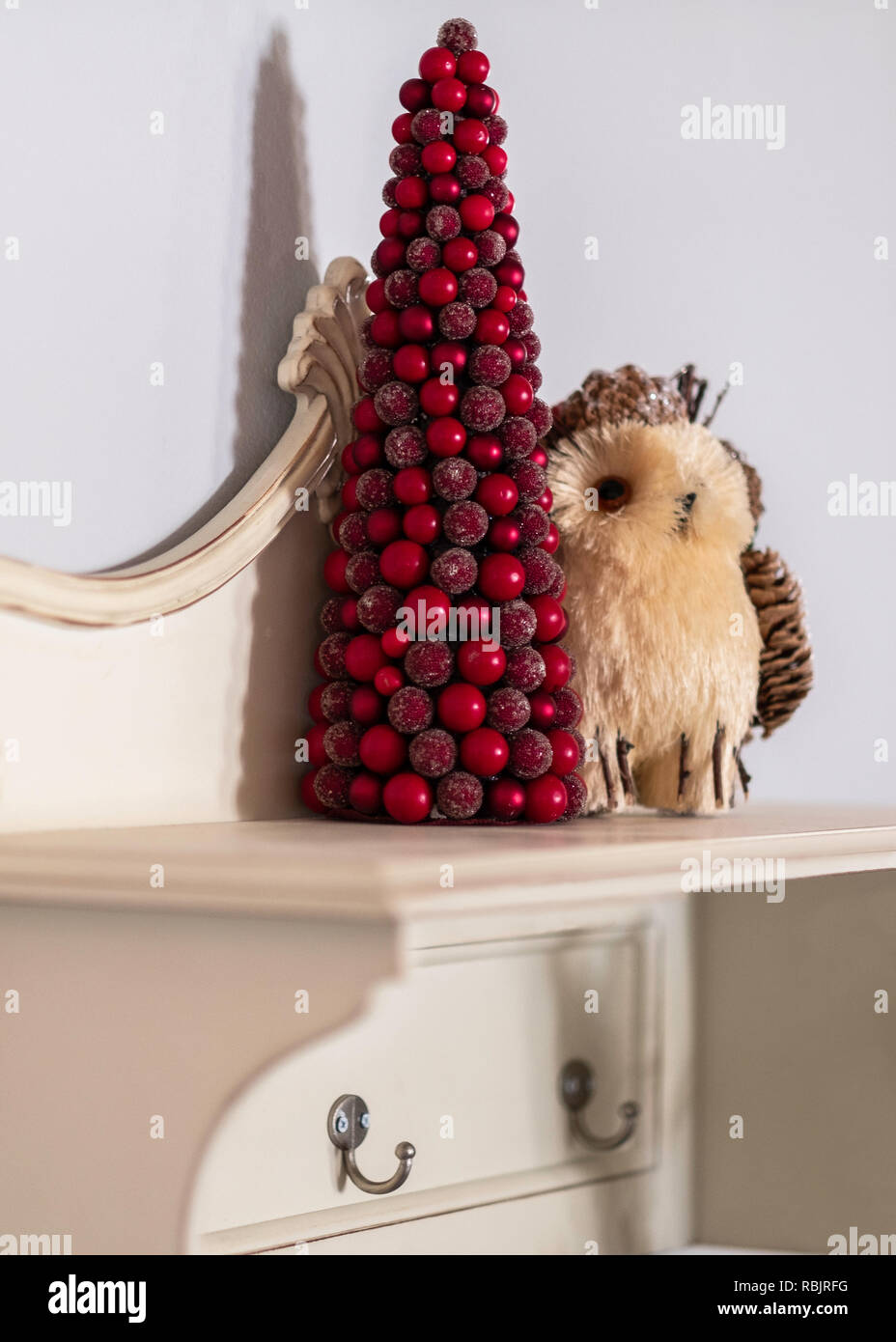 Eine rote Tischplatte Weihnachtsbaum und Eule Dekorationen an der Wand Regal. Stockfoto