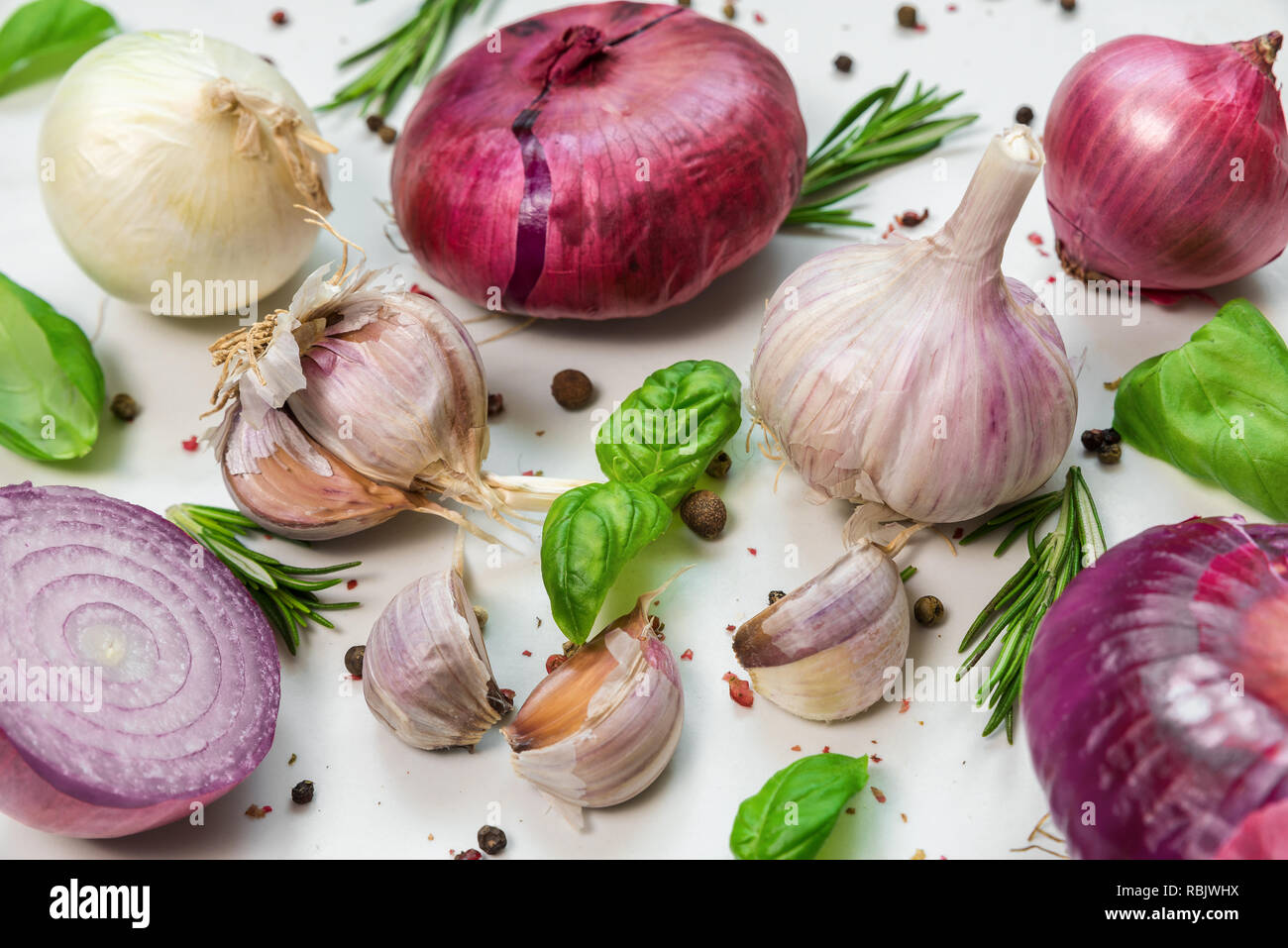 Die Zusammensetzung von Lebensmitteln aus Knoblauch, Zwiebeln, Basilikum, Rosmarin und Pfeffer auf weißem Hintergrund.. Kochen Konzept Stockfoto