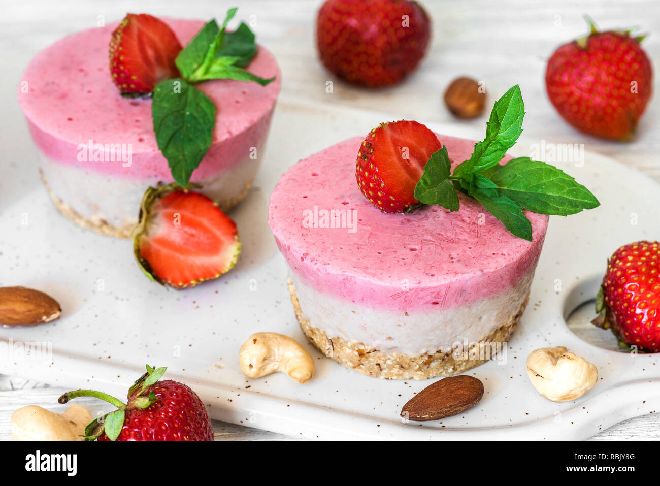 Vegan raw strawberry Cheesecake mit frischen Beeren, Minze und Muttern. Gesunde vegane Ernährung Konzept Stockfoto