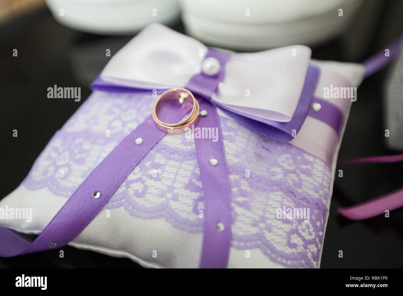 Ein paar Trauringe auf einer weiß-violetten Kissen Stockfoto