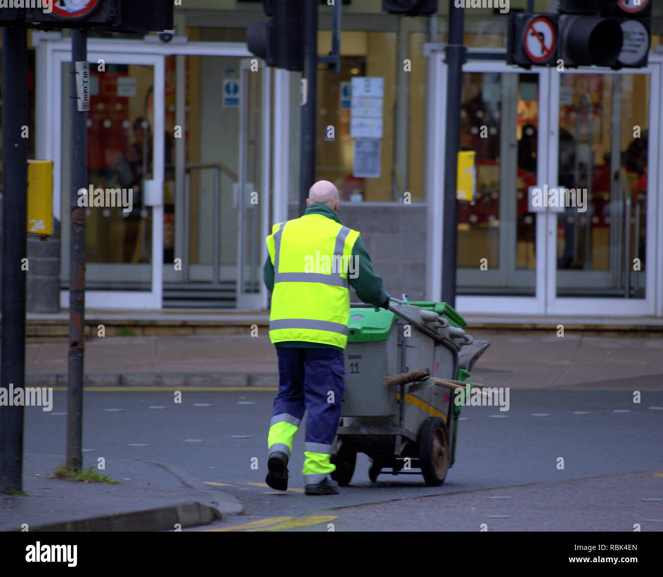 Müllmann Street Sweeper Kreuzung Straße schieben Staub Warenkorb mit Bürsten Stockfoto