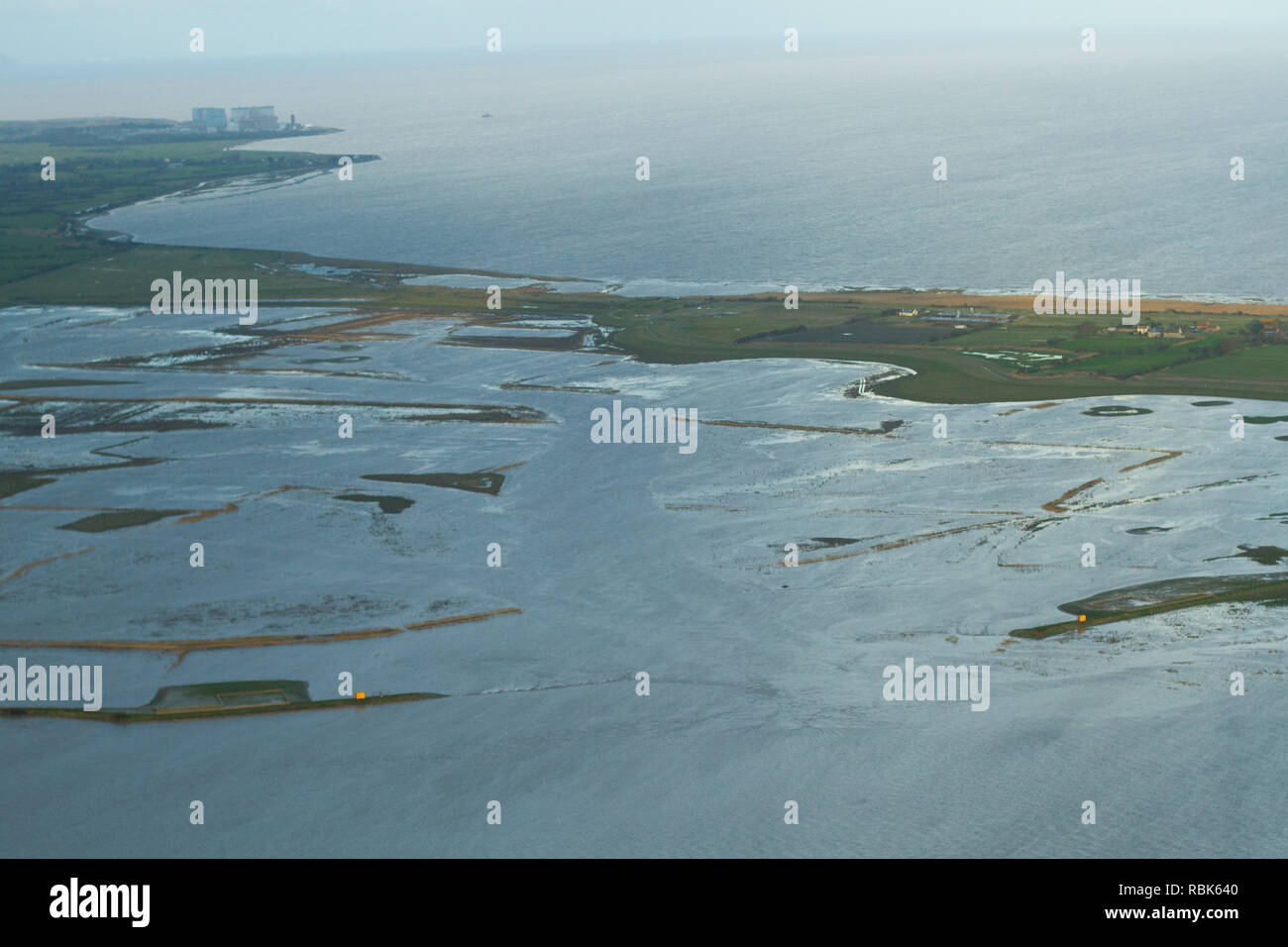 Luftaufnahme von Steart Sümpfen und Feuchtgebieten Wildfowl Trust Naturschutzgebiet mit Hinkley Point Kernkraftwerk im Hintergrund, Somerset, Großbritannien, Februar 2015. Dieser Bereich hat die Flut erlaubt neue Salzwiesen Lebensraum zu schaffen, und ist ein Beispiel für Managed Rückzug. Stockfoto