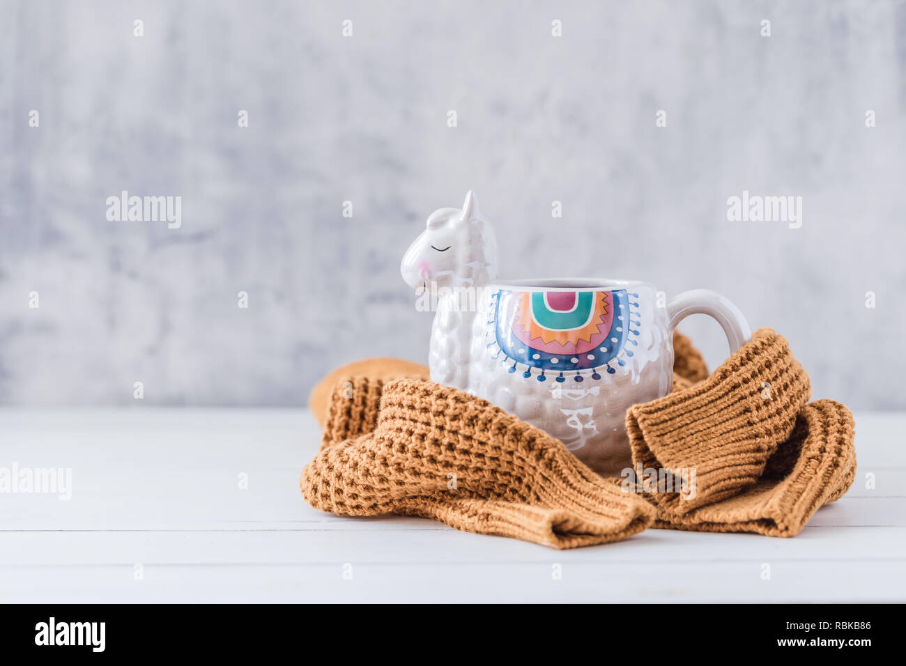 Bunte Llama geformte Tasse mit strickpullover auf die weiße Holztisch, getönt Stockfoto
