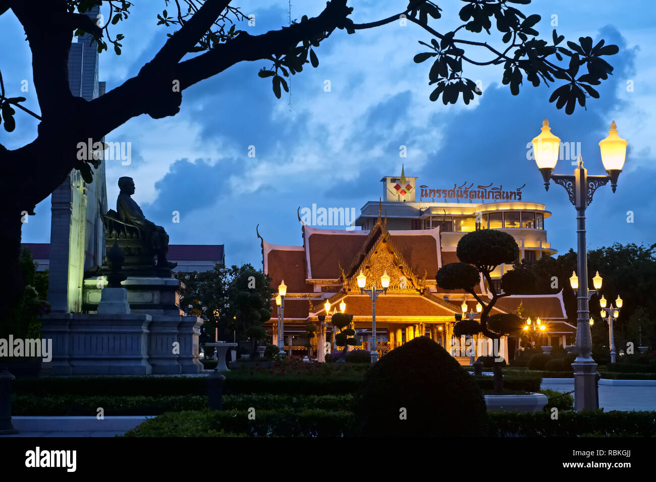 Eine Statue eines sitzenden König Rama III. mit Blick auf die Rama III. Memorial Park, Bangkok, Thailand; Hintergrund: Royal Pavilion Mahachetsadabodin; in der Dämmerung Stockfoto